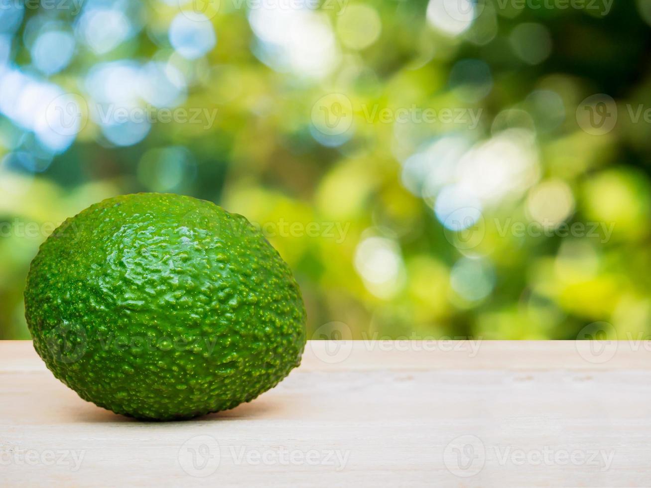 abacate no piso de madeira sobre bokeh de natureza verde foto