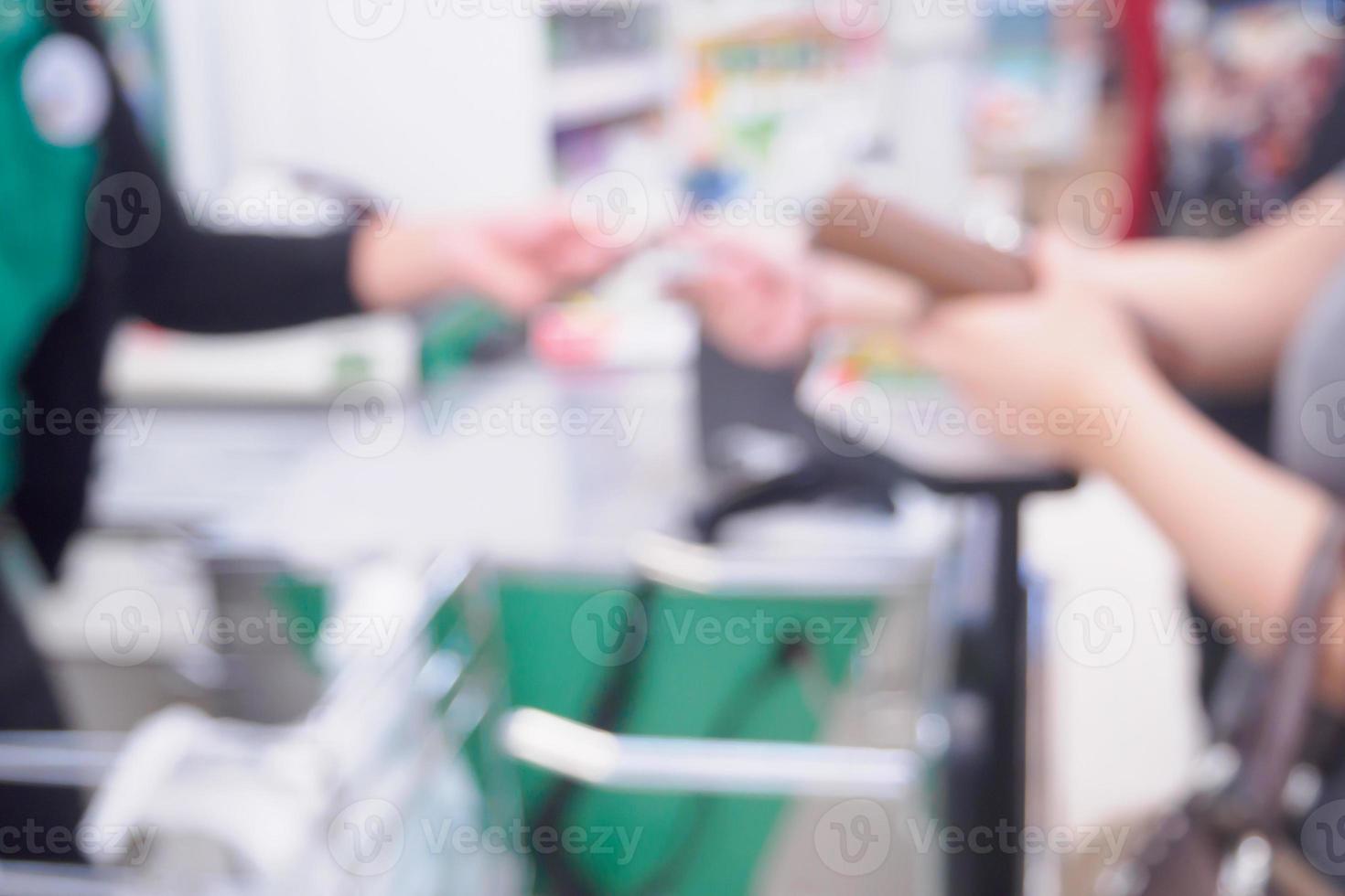 borrar a mão do cliente feminino dando cartão de crédito ao caixa no caixa do supermercado fundo desfocado foto