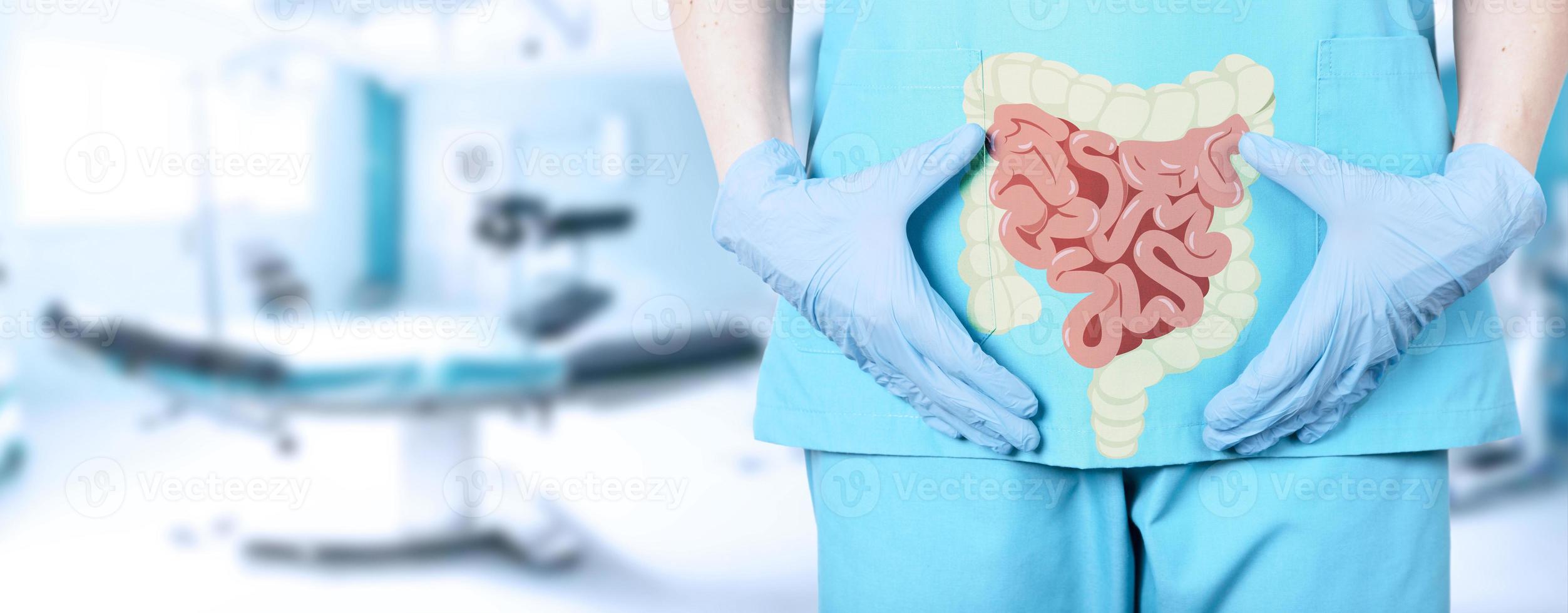 close-up de uma médica cirurgiã em um uniforme médico e um ícone do intestino com um intestino grosso no fundo da mesa de operação no hospital, fundo desfocado macio. foto