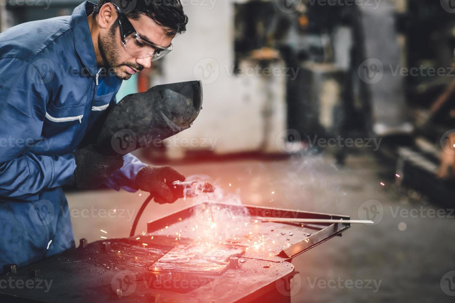 trabalhador da indústria tig soldagem de aço com máscara de segurança para proteger a visão na fábrica de metal. foto