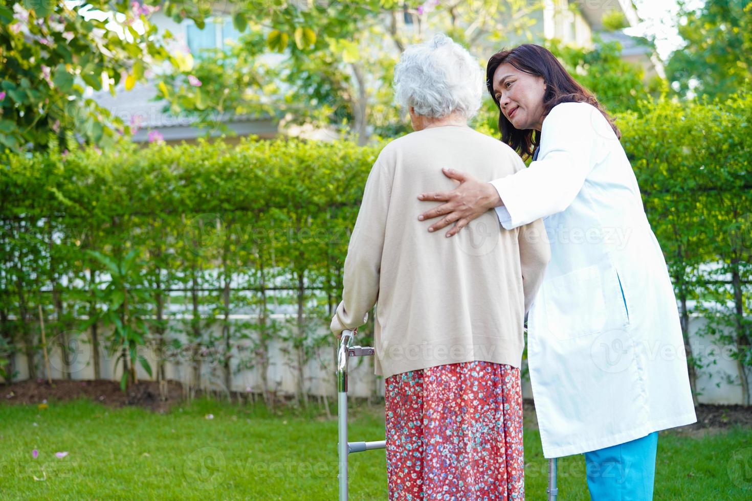 médico ajuda paciente idosa asiática com deficiência andar com caminhante no parque, conceito médico. foto