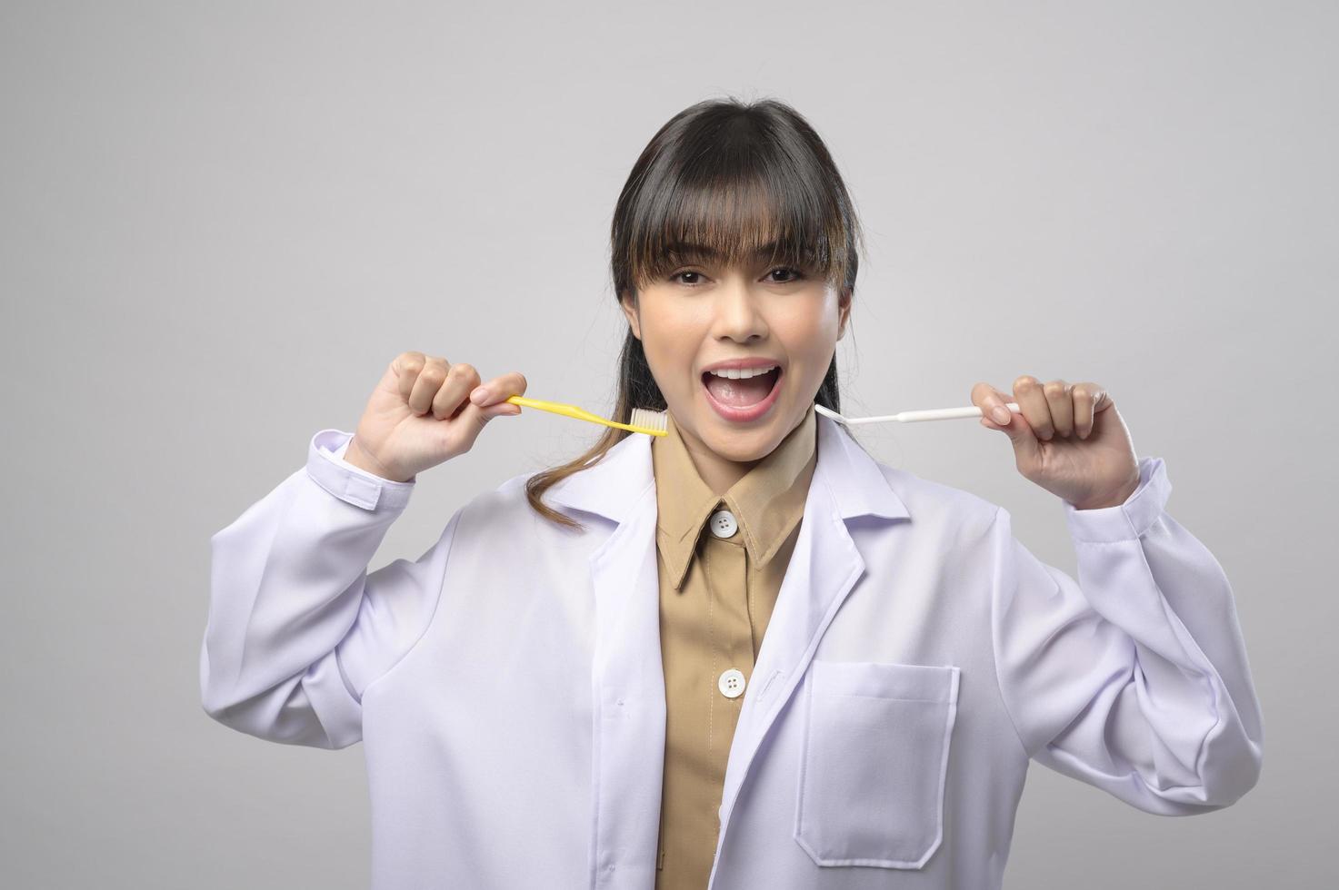 jovem dentista feminina sorrindo sobre estúdio de fundo branco foto