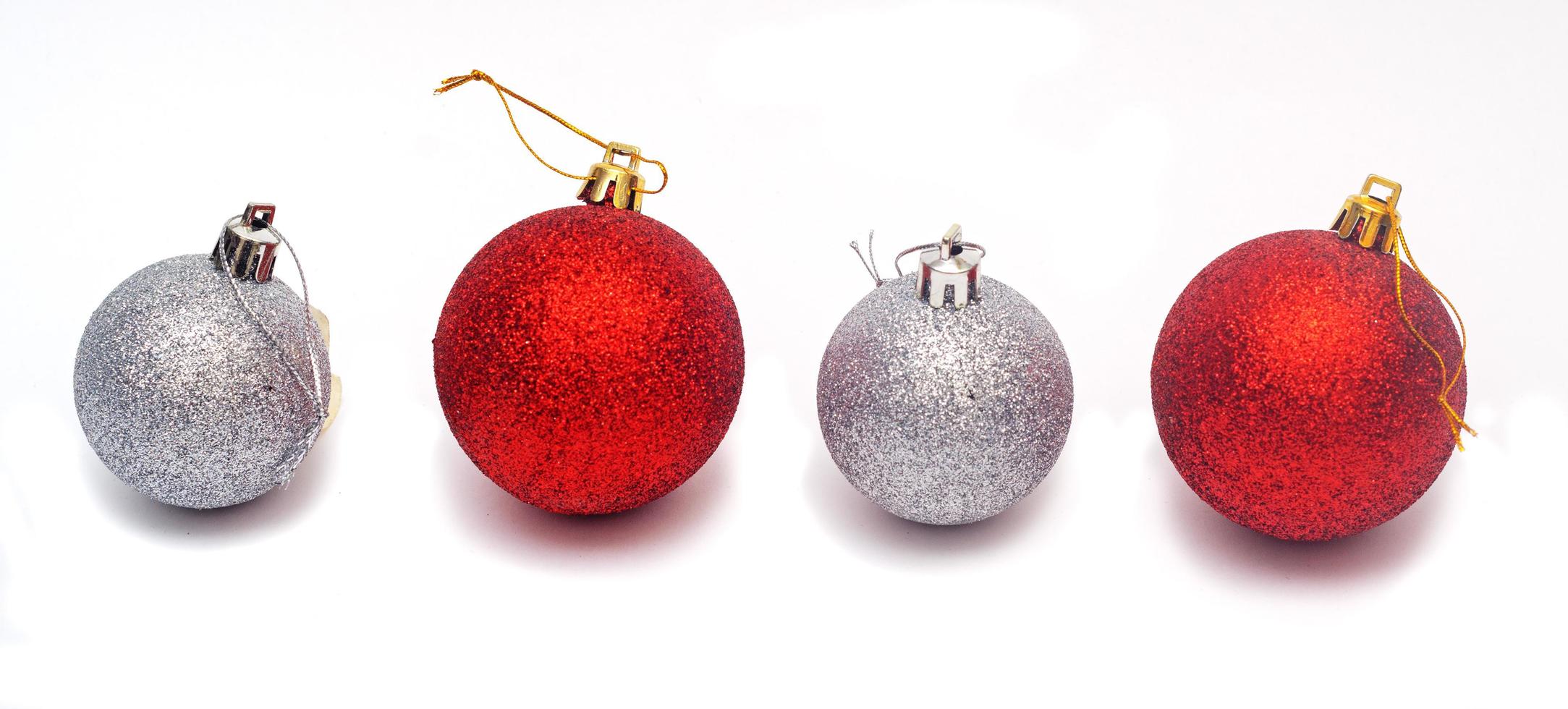 linha de duas bolas de Natal vermelhas e duas prata isoladas no fundo branco. foto