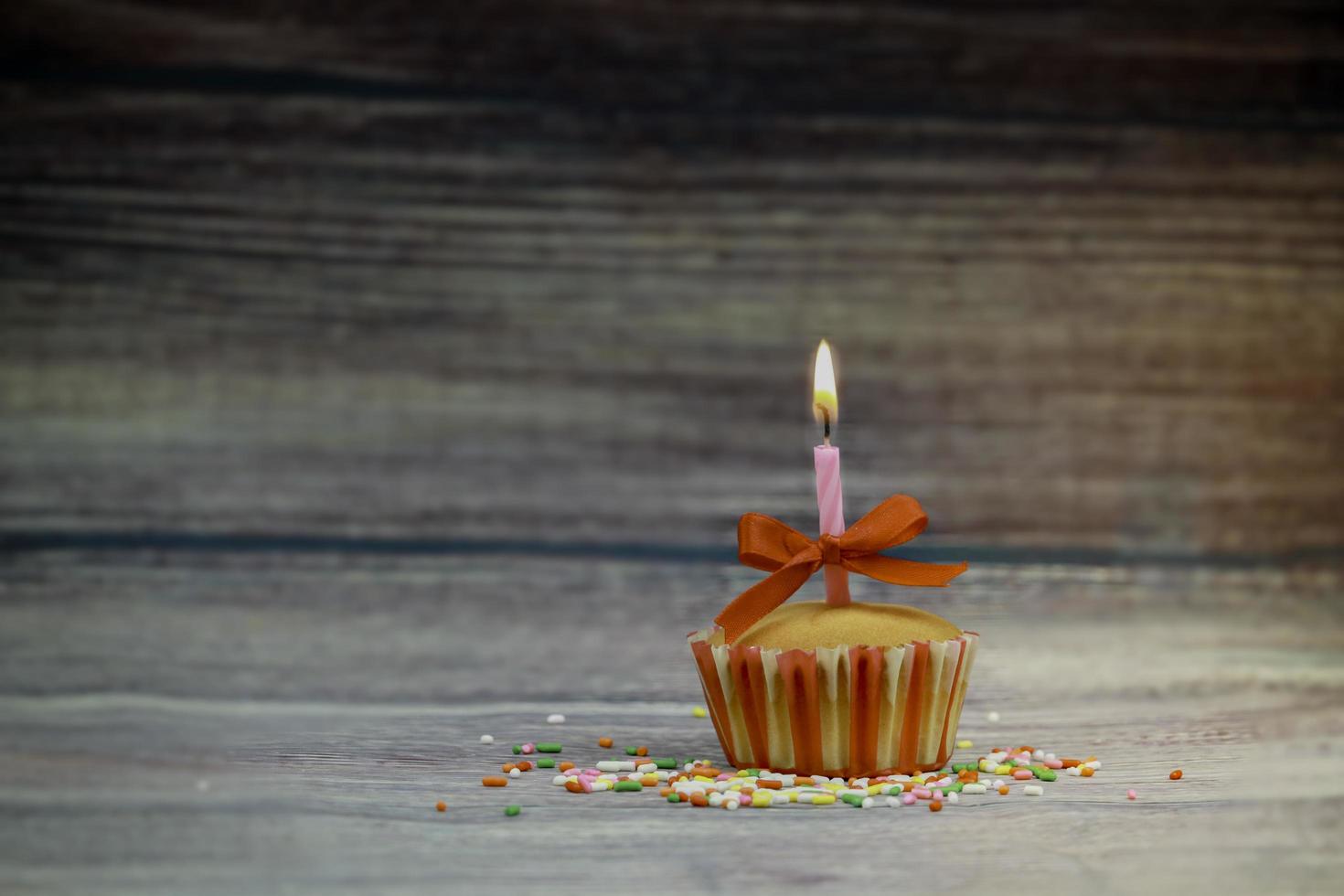 feliz aniversário cupcake e vela de arco na mesa em fundo de madeira com espaço de cópia. conceito de fundo de feliz aniversário de comida fofa foto