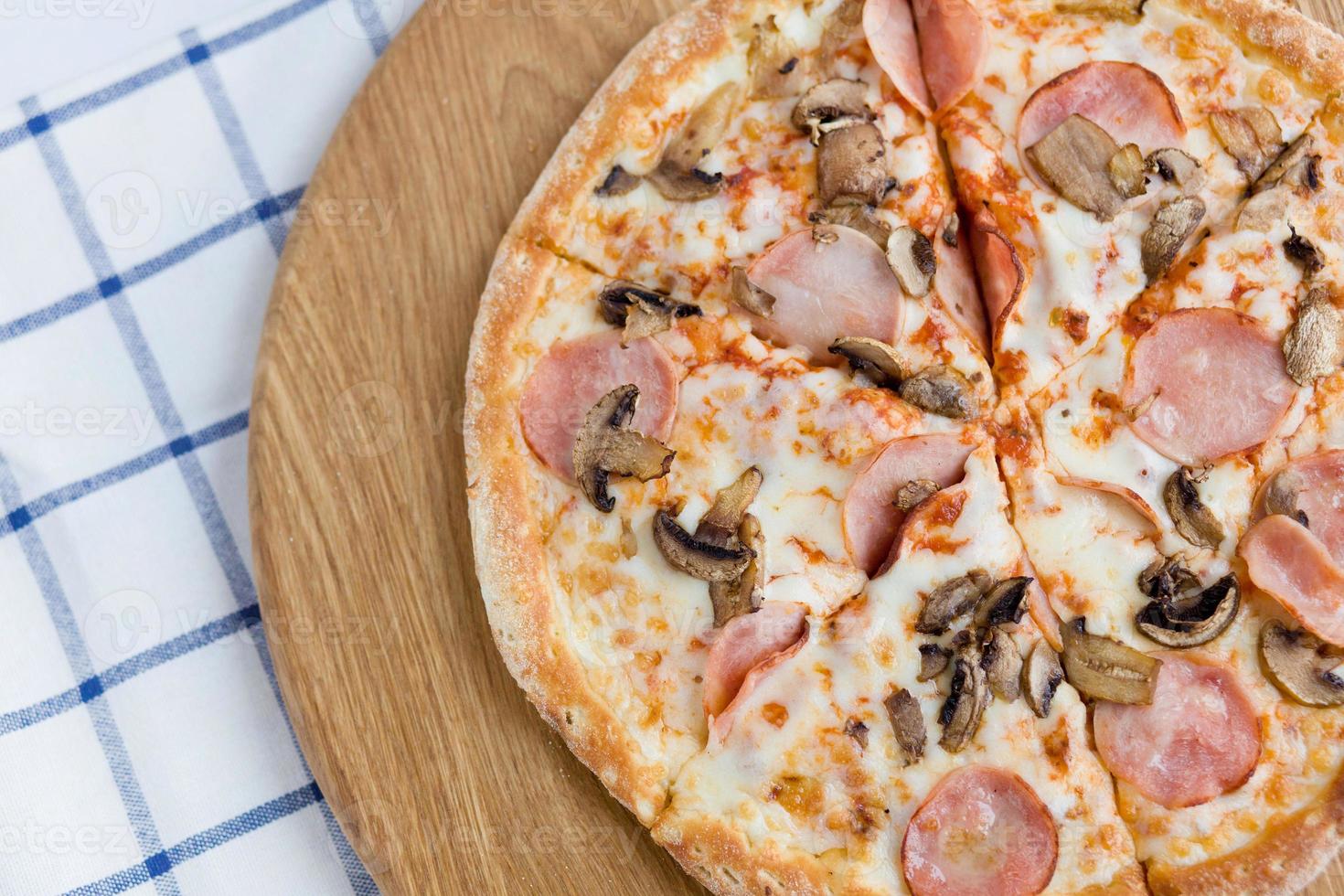 pizza com presunto em uma massa grossa em uma bandeja de madeira, vista superior. foto de comida para pizzaria, cardápio, catálogo, banner, folheto