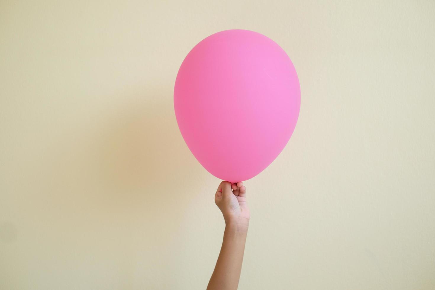 feche o filho da mão segurando o balão rosa isolado no fundo branco. foto