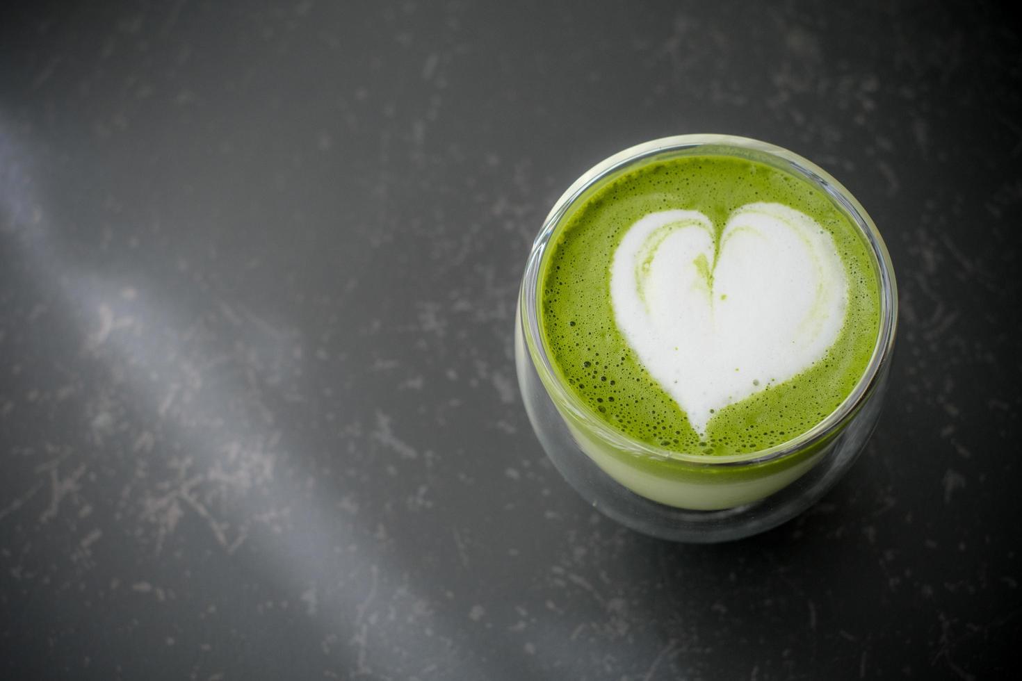 vista superior da arte de latte de chá verde matcha quente em vidro de parede dupla na mesa no café. postura plana. foto