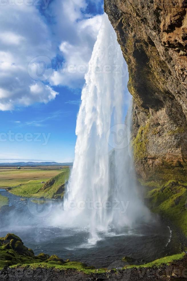 close-up de seljalandsfoss fluindo da montanha contra o céu azul nublado foto