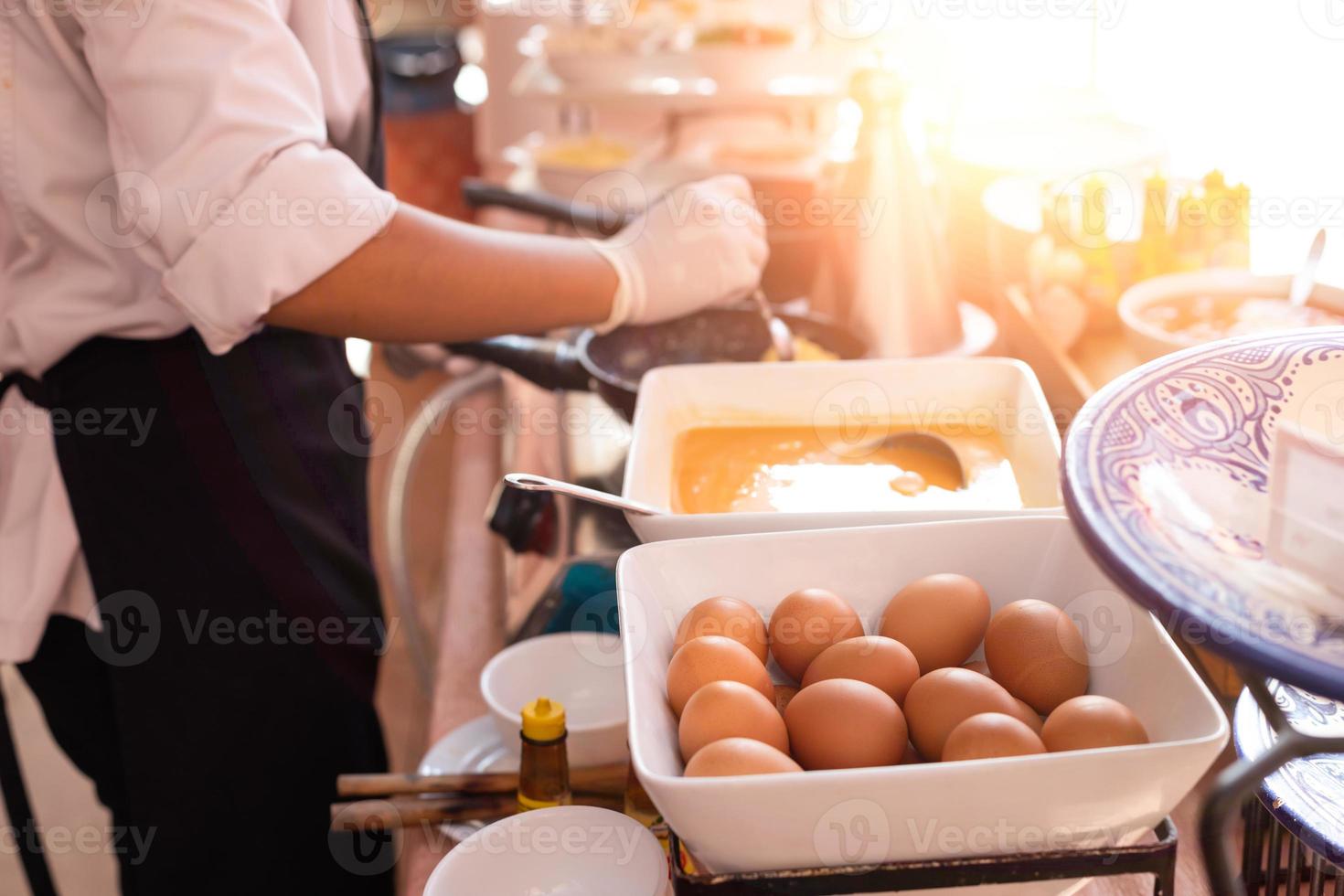 ovos preparados em close-up fazem omeletes no café da manhã com o chef cozinhando ao fundo foto