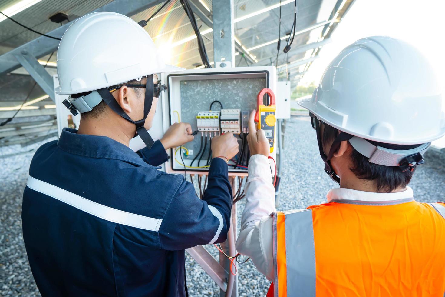 trabalhadores usam alicate amperímetro para medir a corrente de fios elétricos produzidos a partir de energia solar para confirmar a corrente normal foto