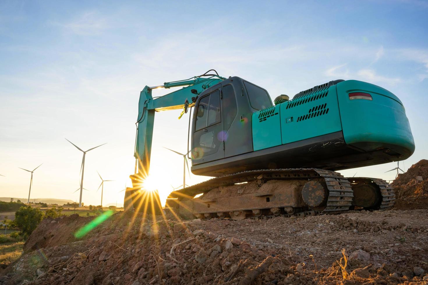 retroescavadeira e turbinas eólicas que estão gerando eletricidade em segundo plano, o conceito de recursos sustentáveis, lindo céu com turbinas de geradores eólicos, energia renovável foto