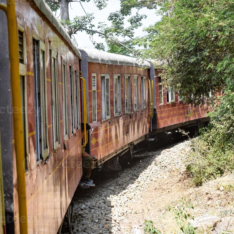 trem de brinquedo movendo-se nas encostas das montanhas, bela vista, uma montanha lateral, um vale lateral movendo-se na ferrovia para a colina, entre a floresta natural verde. trem de brinquedo de kalka para shimla na índia foto