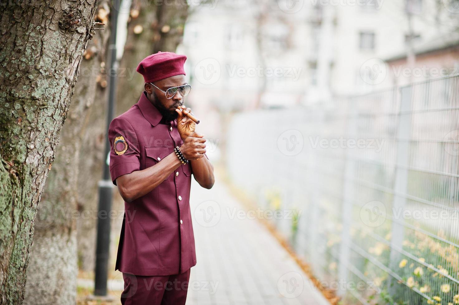 retrato de militar americano africano em uniforme vermelho, sungalasses e boina. capitão fuma charuto. foto