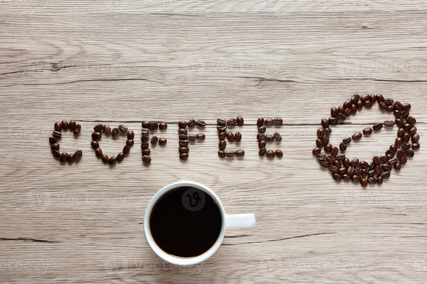 os grãos de café da vista superior são organizados em termos alfabéticos, café e xícara de café colocados em uma mesa de madeira. foto