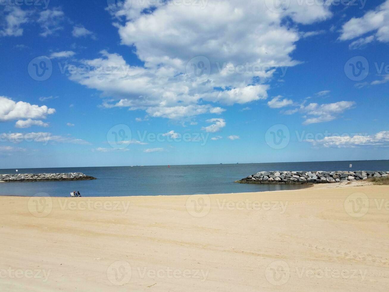 areia e pedras e água e nuvens na praia foto