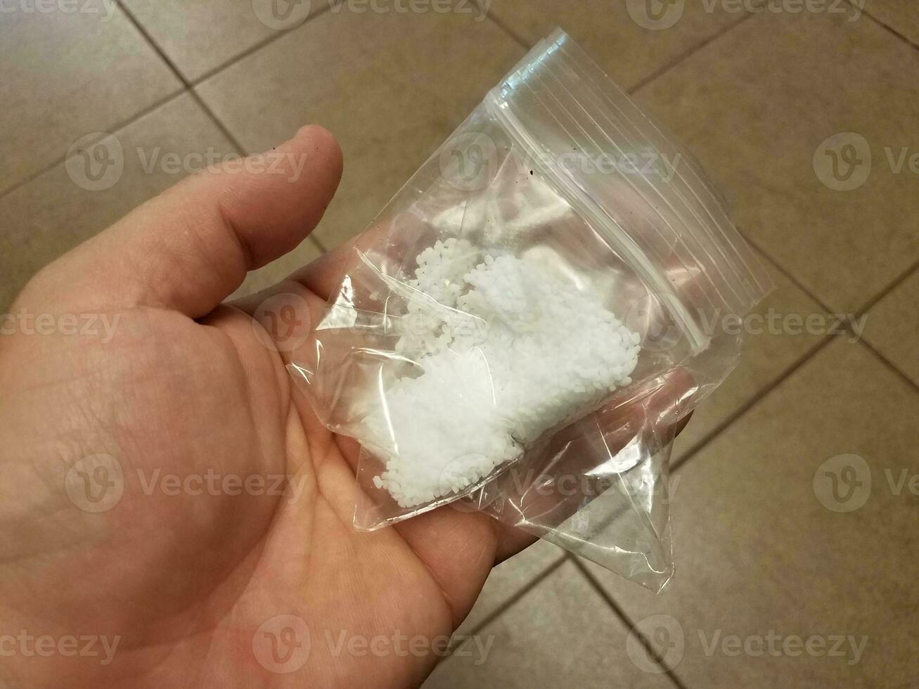 mão segurando o saco plástico com sal branco foto