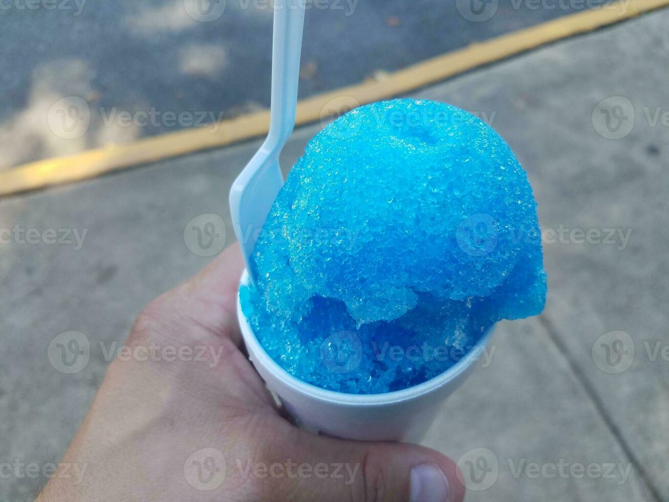 mão segurando o cone de neve azul em um copo foto