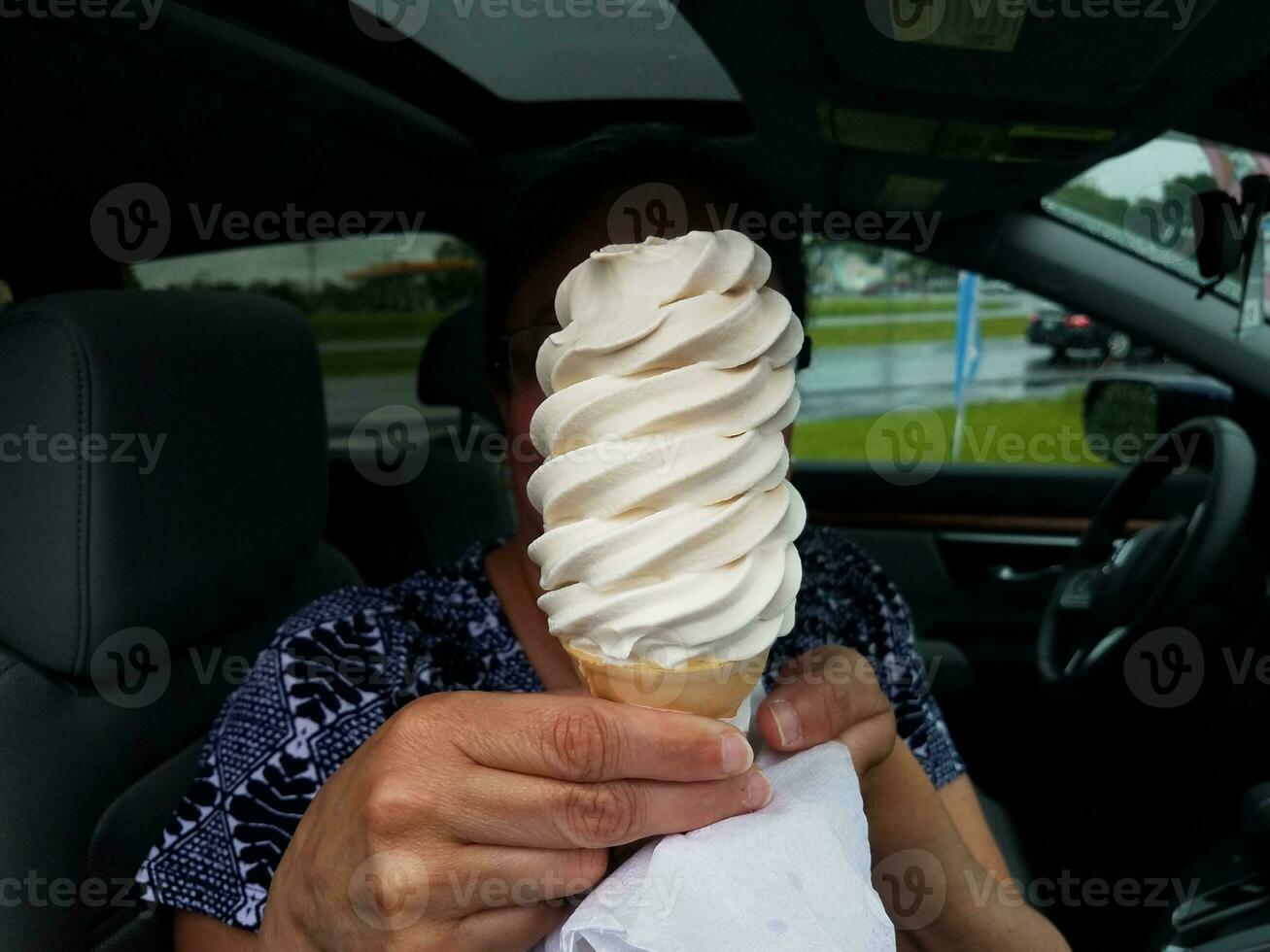 mulher segurando grande casquinha de sorvete de baunilha no carro foto