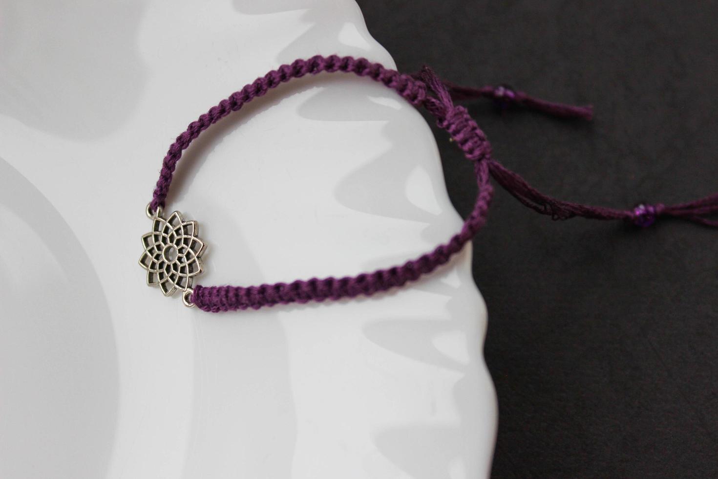 pulseira trançada roxa com chakra sahasrara na borda de um prato branco como a neve foto