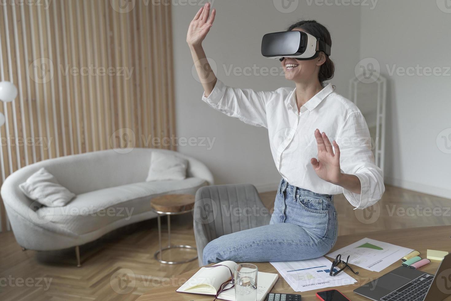 empresária em fone de ouvido vr na cabeça tocando objetos 3d enquanto trabalhava no escritório moderno foto