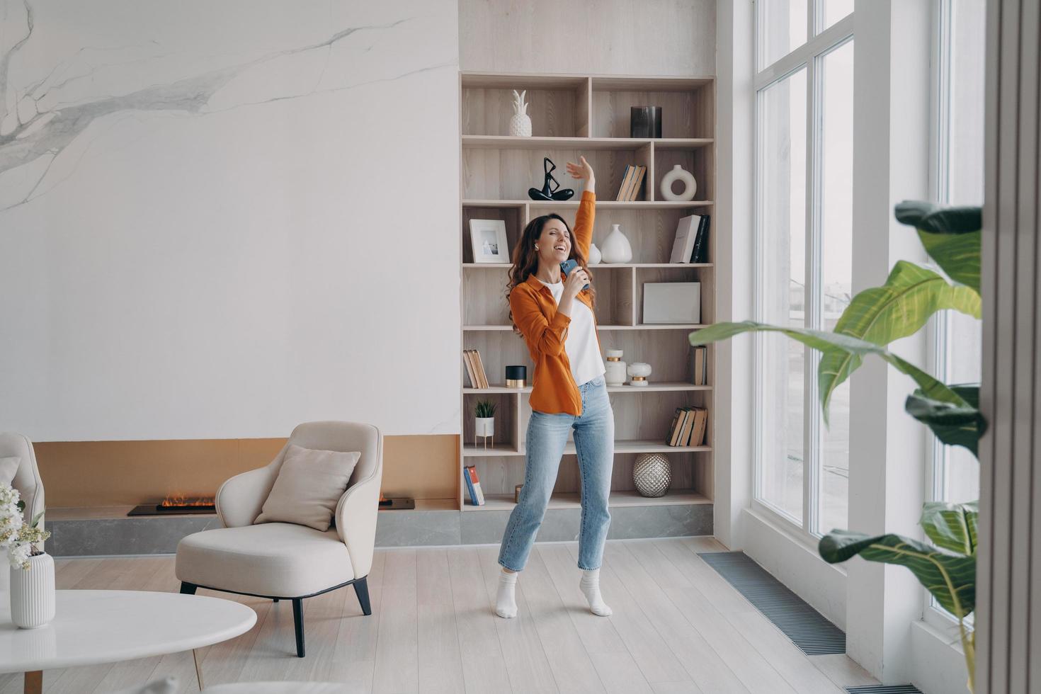 garota se divertindo loucamente em sua sala de estar. relaxamento e dança em casa, expressões emocionais. foto