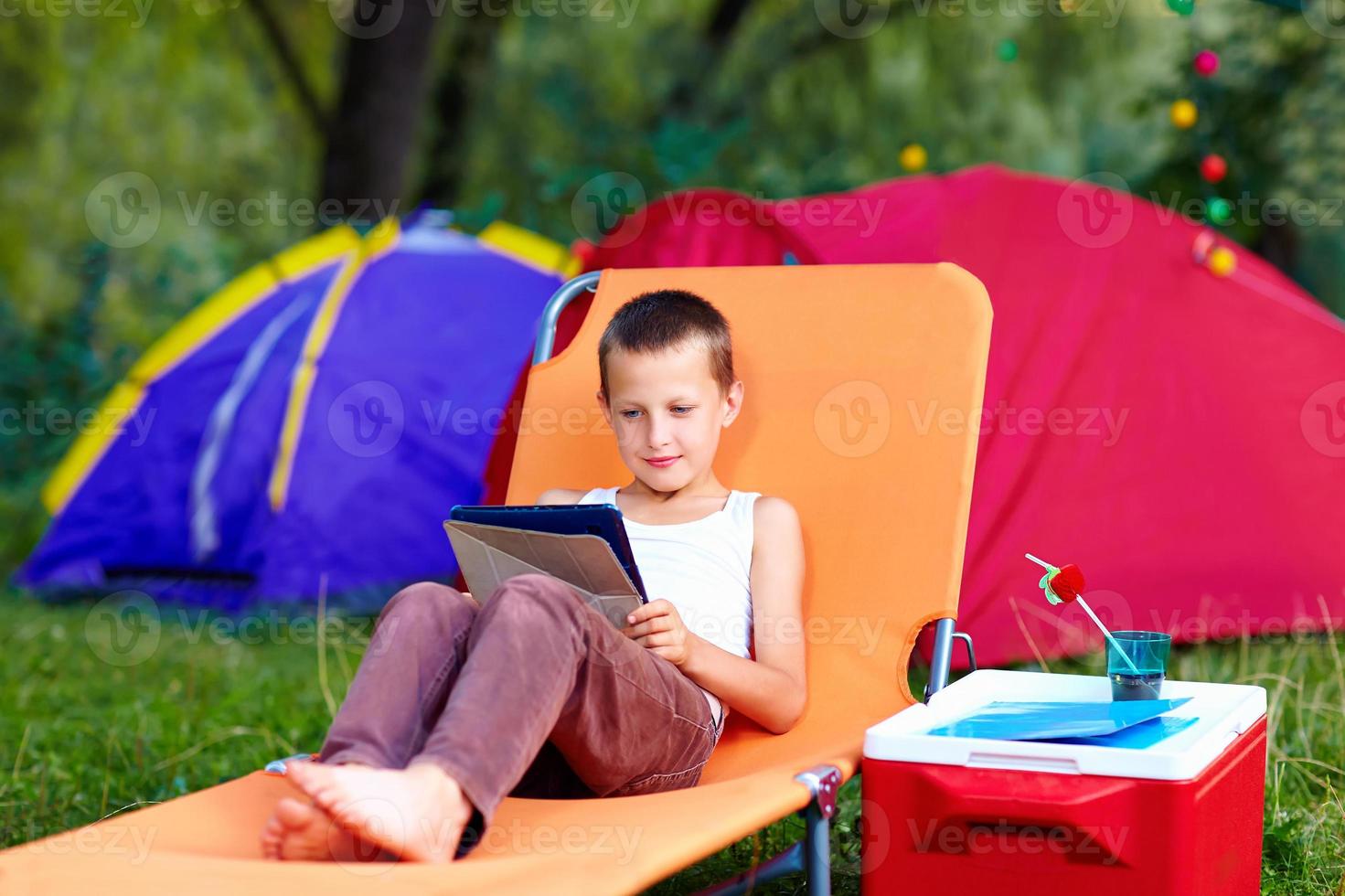 jovem rapaz no acampamento de verão, relaxante com tablet foto
