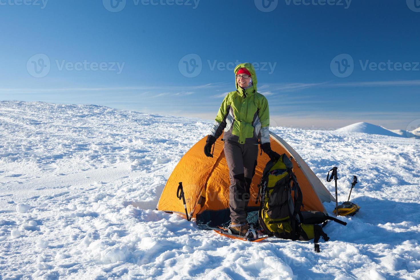 mulher posando na barraca laranja nas montanhas de inverno foto