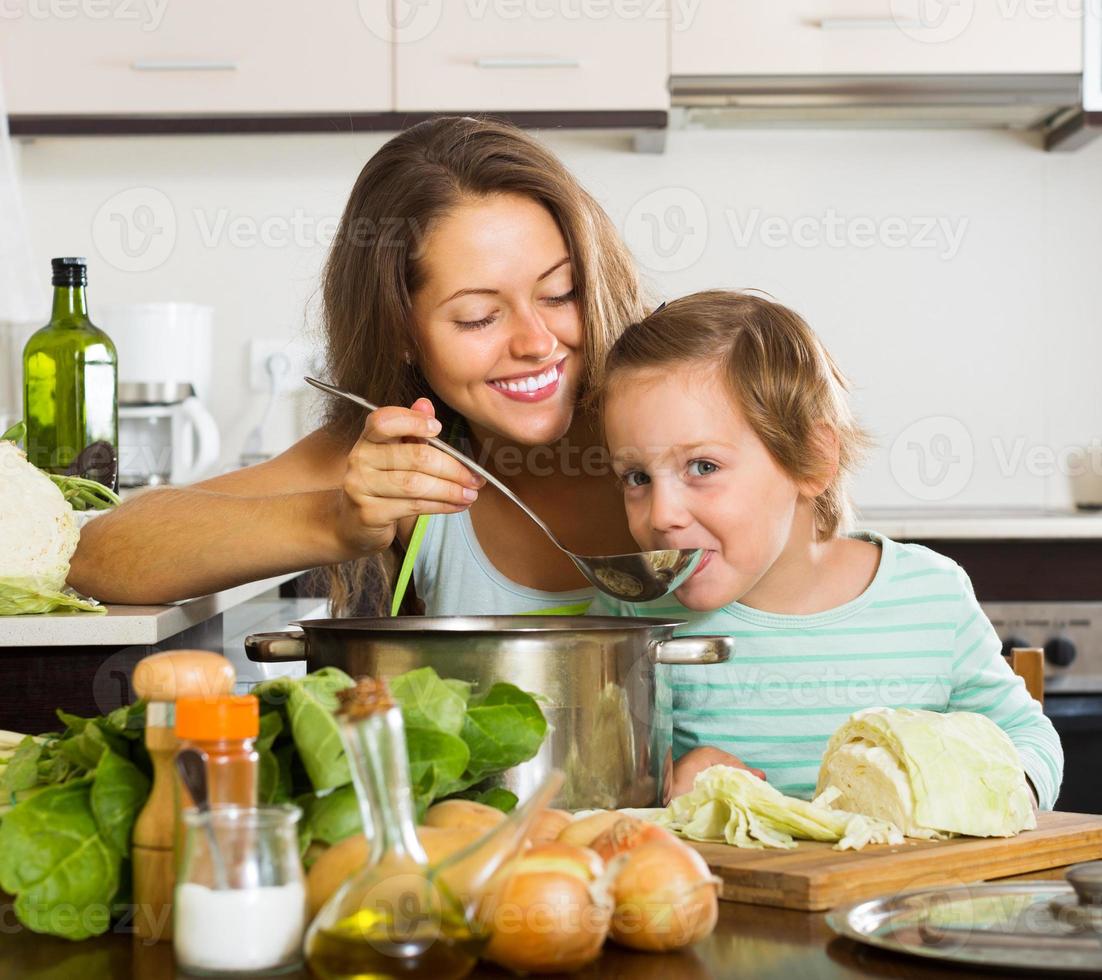 mãe feliz com a filha cozinhando juntos foto
