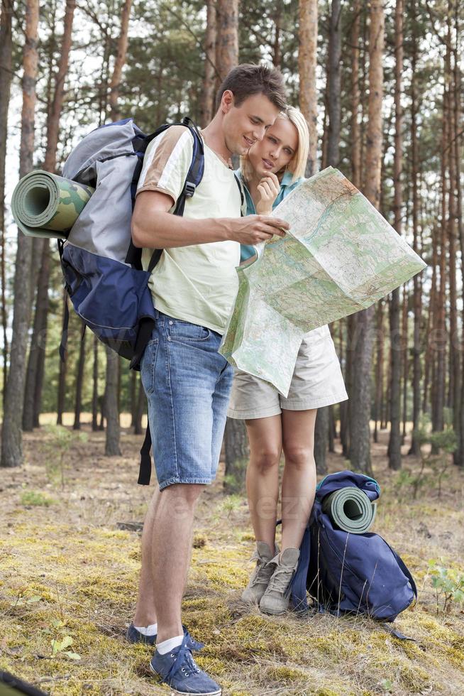 comprimento total dos jovens caminhadas casal lendo o mapa na floresta foto