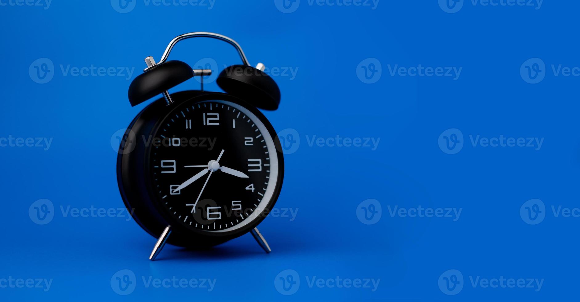 despertador preto em fundo azul com espaço de cópia. conceito de tempo. foto