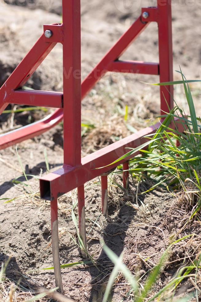 pá vermelha em forma de garfo no jardim. pá milagrosa, ferramenta útil. cultivador manual. o cultivador é uma ferramenta eficaz para a lavoura. afrouxamento da cama. ferramentas agrícolas sustentáveis. foto