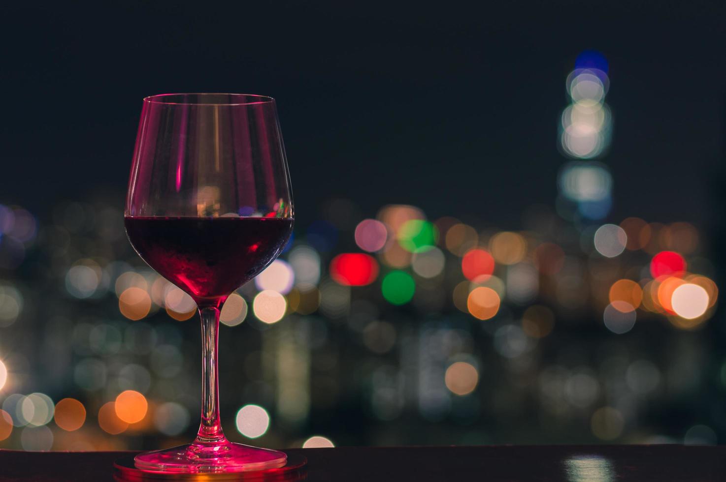 luz colorida brilha em um copo de vinho tinto foto