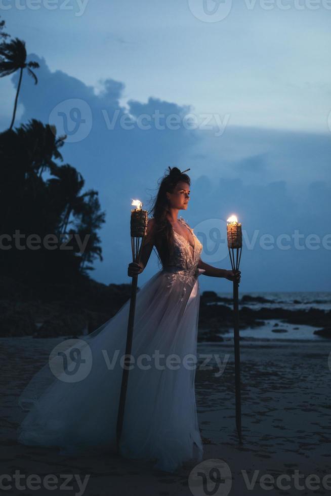 linda noiva com tochas na praia foto