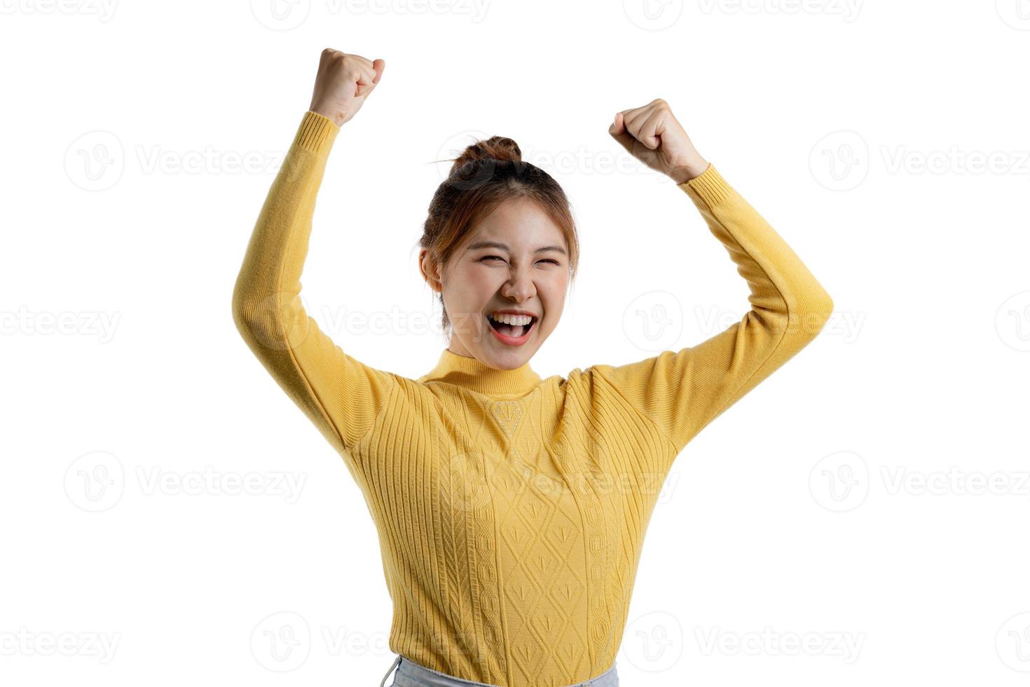 retrato de uma linda mulher asiática em uma camisa amarela em pé com as mãos para cima de alegria. conceito de retrato usado para propaganda e sinalização, isolado sobre o fundo em branco, copie o espaço. foto