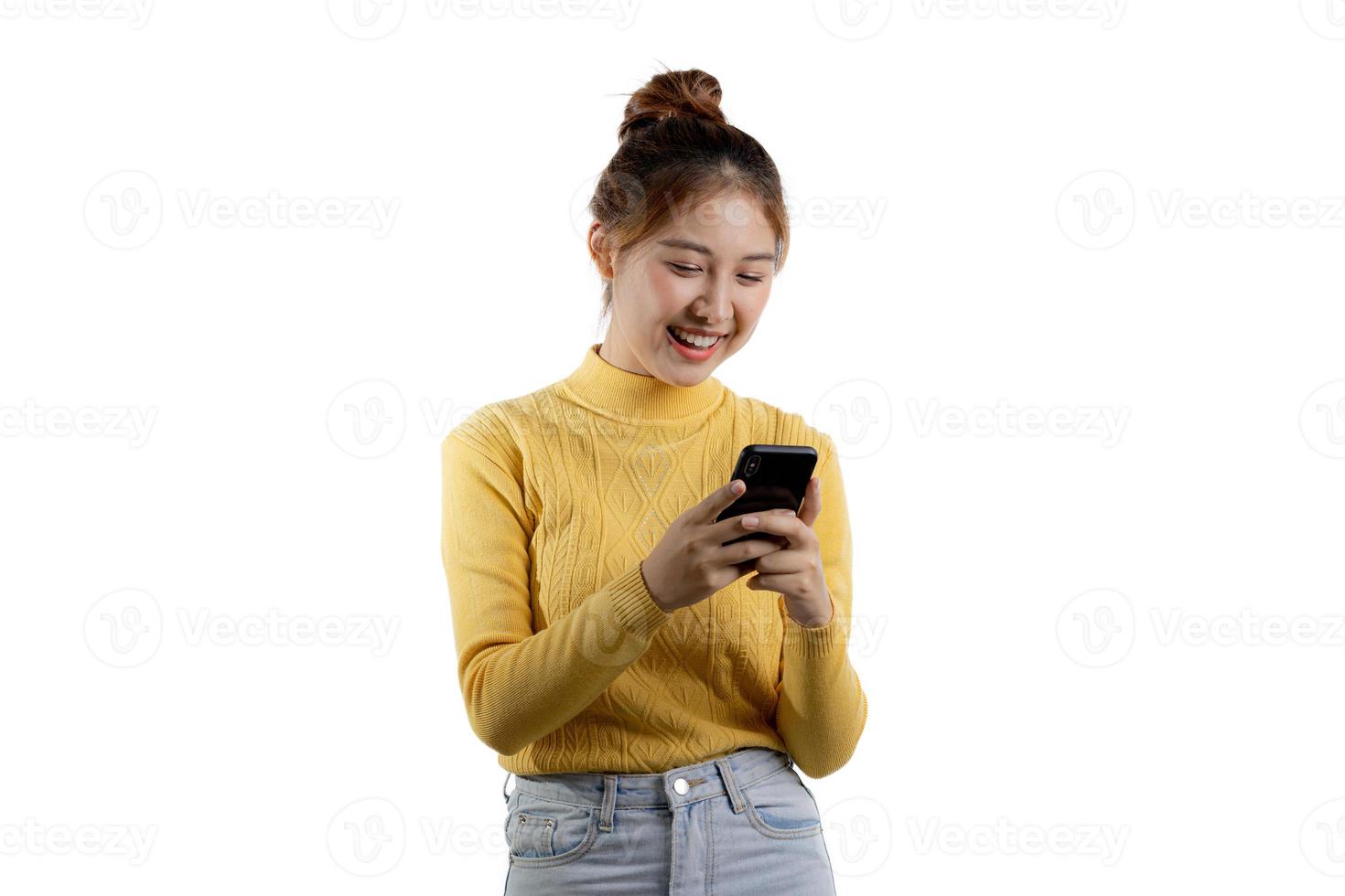 retrato de uma linda mulher asiática de camisa amarela jogando em um smartphone. conceito de retrato usado para propaganda e sinalização, isolado sobre o fundo em branco, copie o espaço. foto