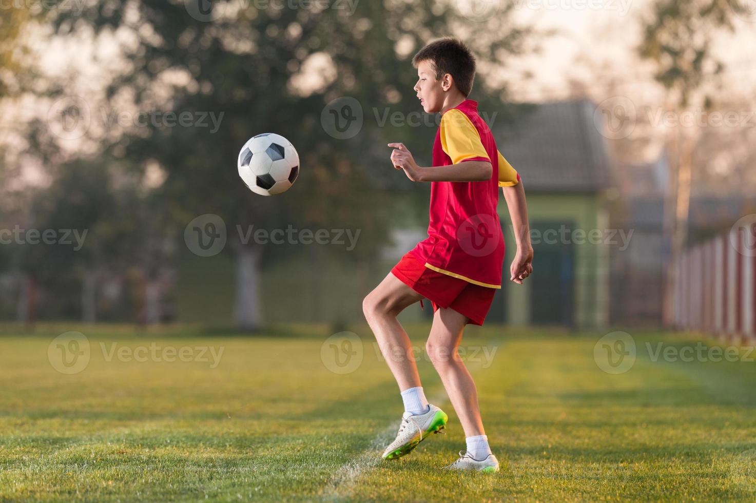 Criança A Jogar Futebol. Um Rapaz Asiático A Dar Pontapés No Ssoccer  Vermelho. Foto Royalty Free, Gravuras, Imagens e Banco de fotografias.  Image 199633197