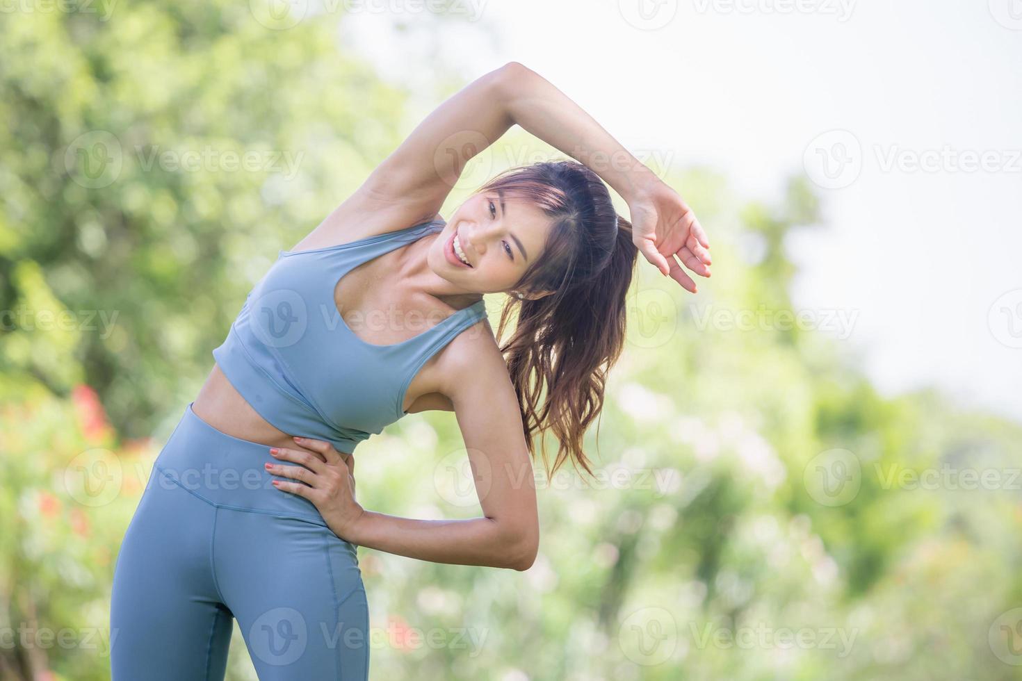 mulher fitness esticando os músculos antes da atividade esportiva, jovem desportista esticando e se preparando para correr no parque foto