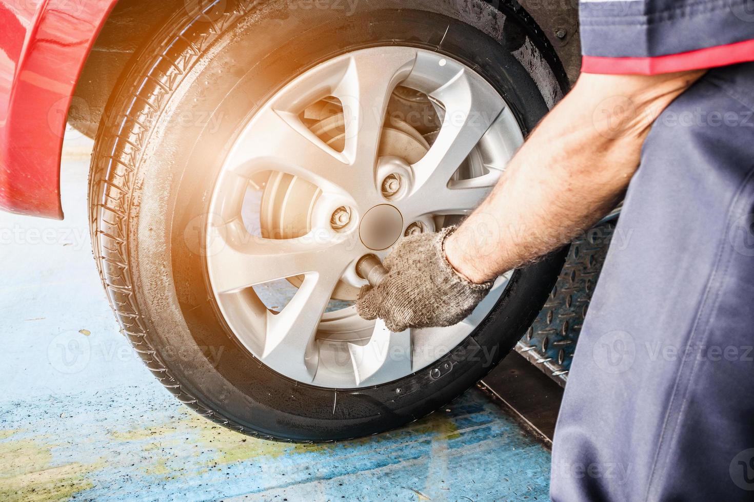 serviço de substituição de pneus, mecânico com chave trabalhando na oficina de reparação de automóveis, trocando a roda do carro foto