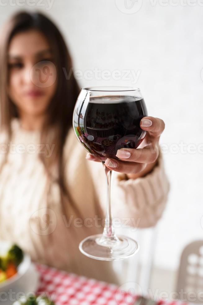 mulher jantando de ação de graças na cozinha de casa comemorando feriado, segurando o copo de vinho foto