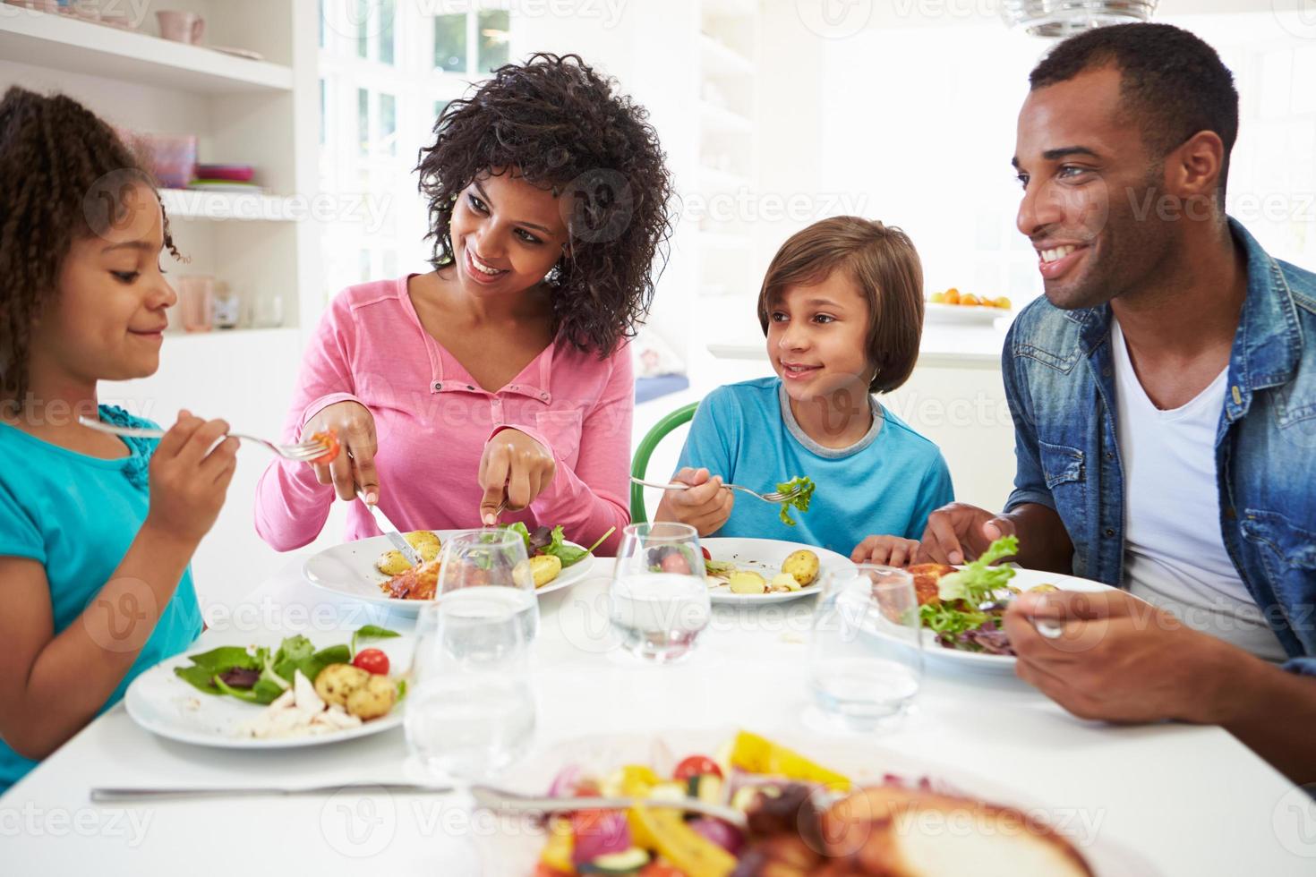 família afro-americana a comer a refeição em casa juntos foto