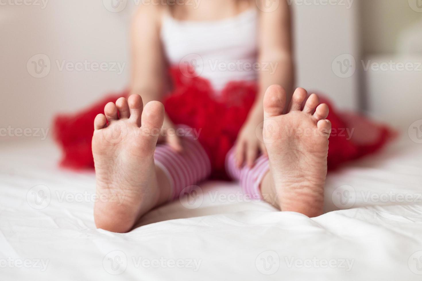 pés da criança na cama de pijama listrado do ano novo foto