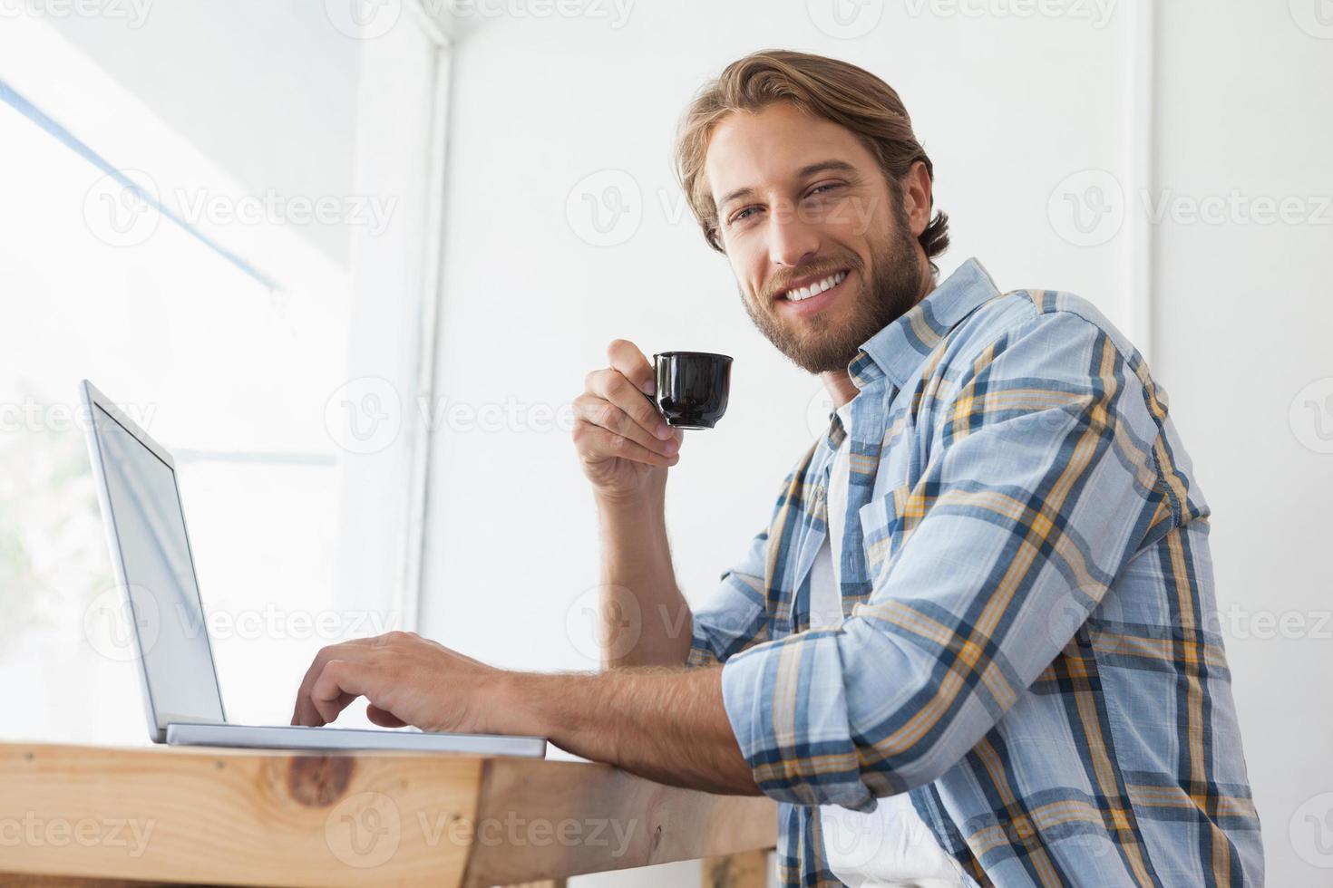 casual homem usando laptop bebendo café expresso foto
