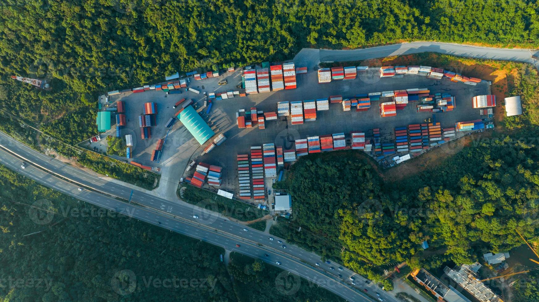 o pátio de contêineres de carga ao lado da estrada e cercado por montanhas, empilhadeira e carga no depósito, carga de trabalho, descarga, transporte, transporte e serviço ao conceito de cliente, logística expressa foto