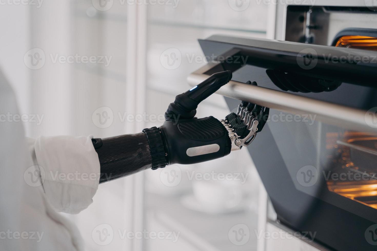 mão cibernética robótica de pessoa com deficiência está abrindo o forno na cozinha. amputado está cozinhando. foto