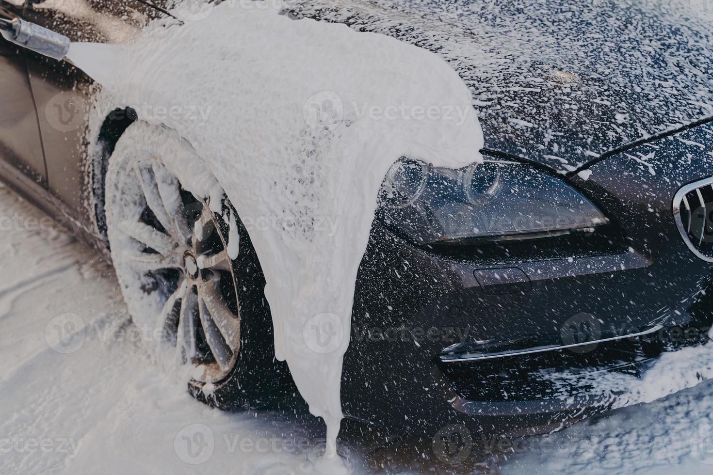 carro preto em espuma de sabão branco na estação de lavagem foto