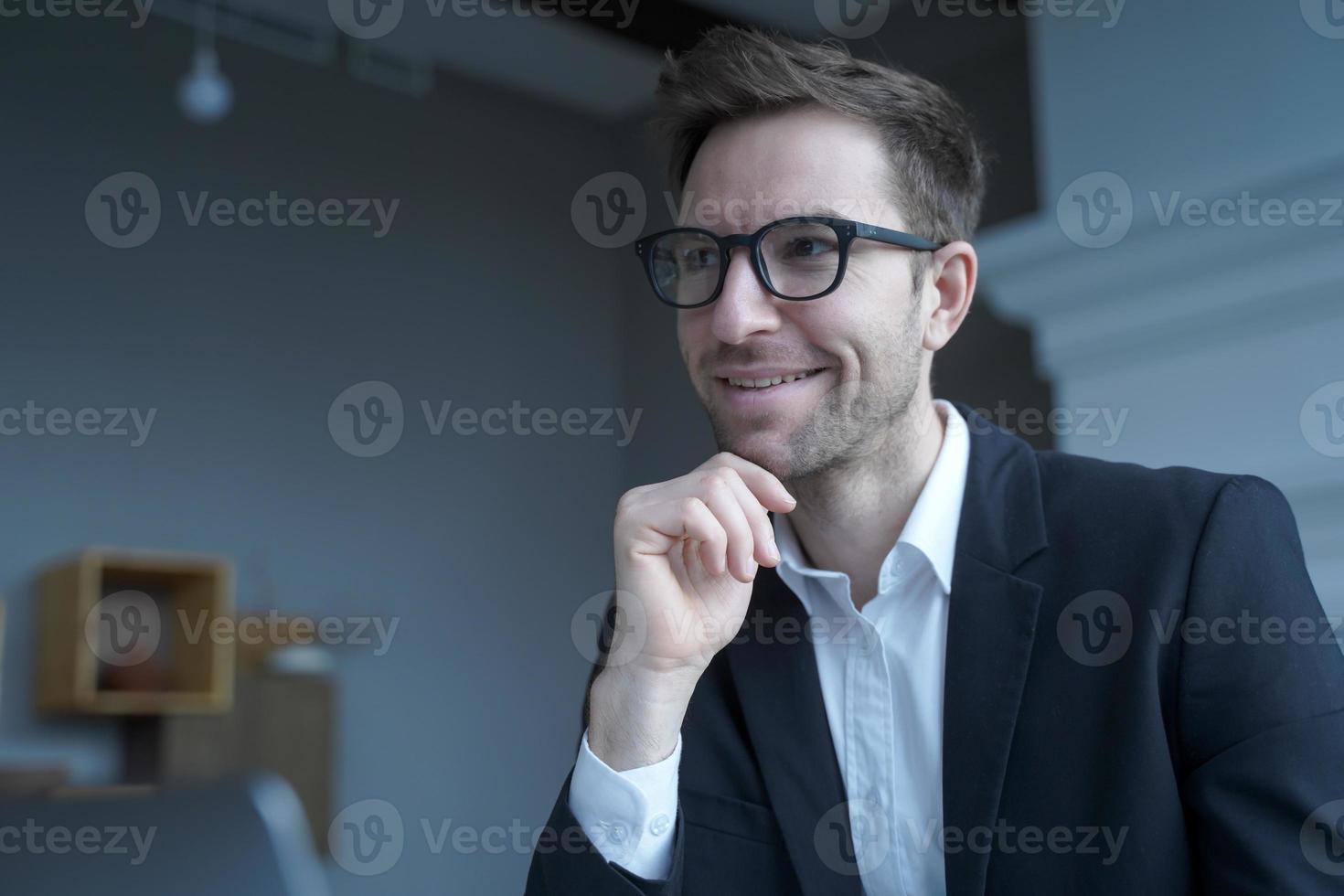 bonito empresário austríaco positivo usando óculos trabalhando remotamente em casa foto