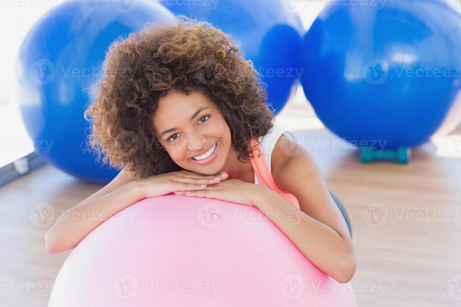 mulher jovem sorridente com bola de fitness no ginásio foto