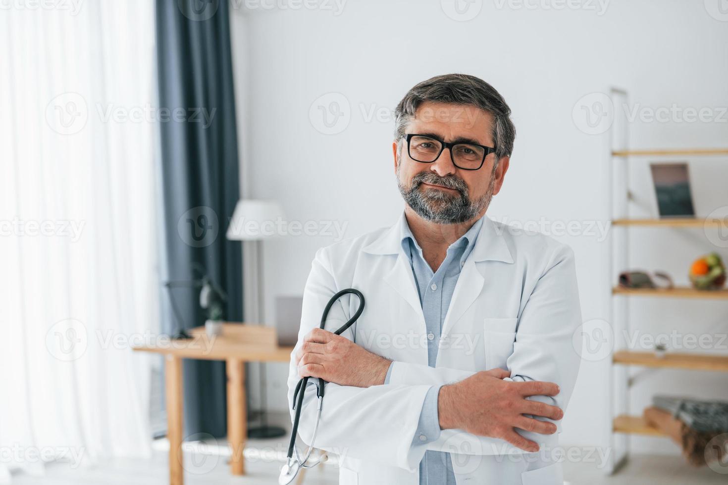 médico masculino está com estetoscópio. trabalhador médico profissional de jaleco branco está no escritório foto