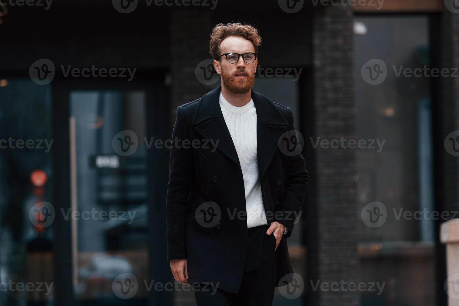 homem elegante com barba e óculos está ao ar livre perto do prédio foto