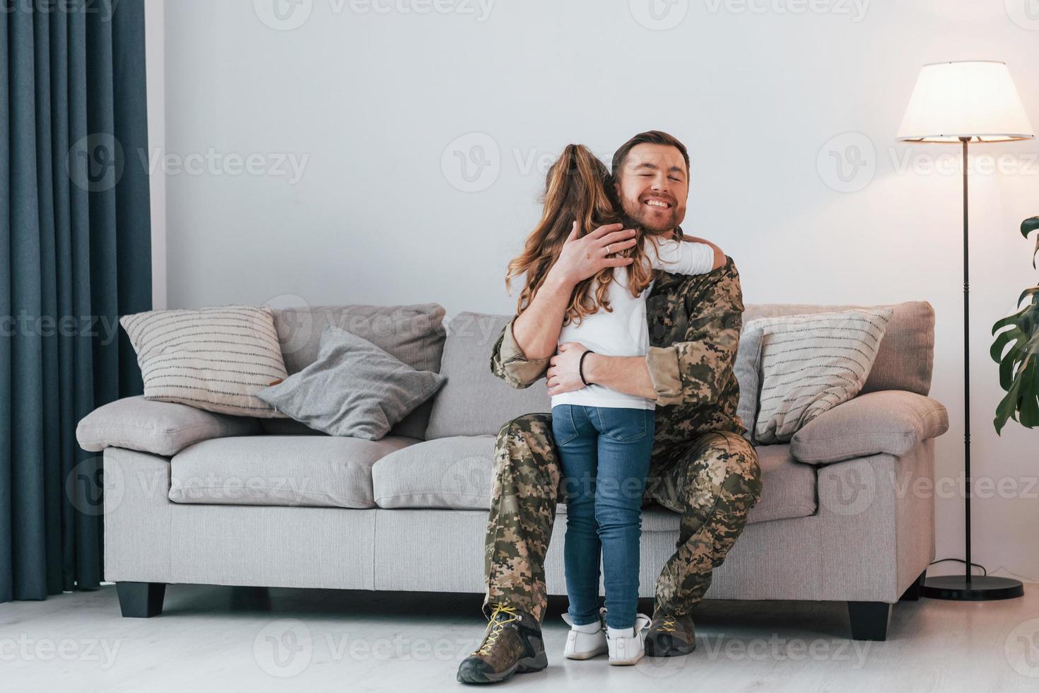 senti sua falta. soldado de uniforme está em casa com sua filha foto